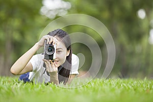 Girl with camera lie down on grass