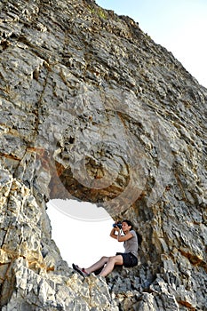 Girl with a camera on a rocky shore