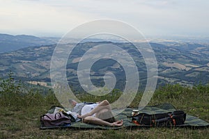 Girl camping in the mountains. Young woman lying on the blanket across the mountain view