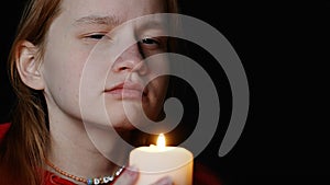 A girl with a candle in her hands is mysteriously examining something