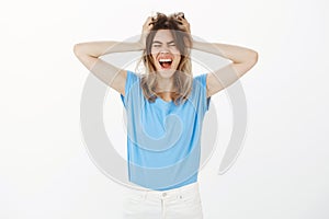 Girl cannot control emotions from happy news. Excited overwhelmed funny woman in blue t-shirt, screaming, making hair