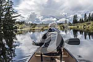 Girl canoeing with Canoe on the lake of two rivers in the algonquin national park in Ontario Canada on sunny cloudy day