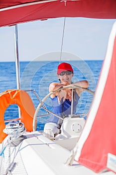 Girl captain on board of sailing yacht on summer cruise. Travel adventure, yachting with child on family vacation.