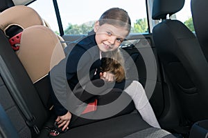 The girl in the car before going to school fastens the seat belt of her seat