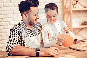 Girl with Carafe in Hands on Father Juice at Home.