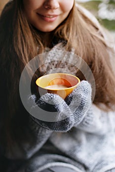 Girl in cardigan holding a cup of coffee. Close-up