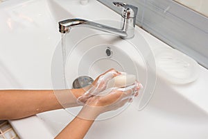 The girl carefully soaps her hands with soap, close-up