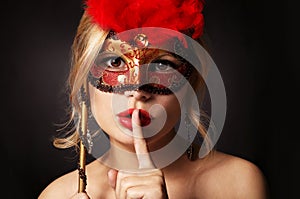 Girl with carnival mask. woman with finger on her red lips showing hush photo