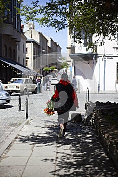 The girl carries a bouquet of orange lilies on the street of the old town