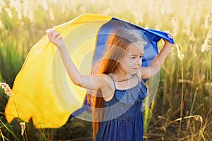 Girl carries fluttering blue and yellow flag of Ukraine in field