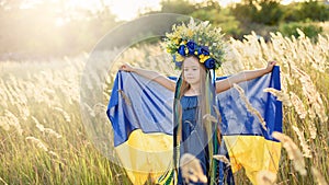 Girl carries fluttering blue and yellow flag of Ukraine in field