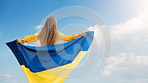 Girl carries fluttering blue and yellow flag of Ukraine in field