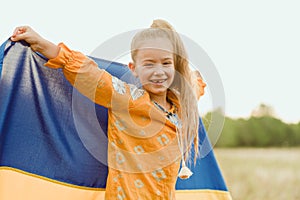 Girl carries fluttering blue and yellow flag of Ukraine in field