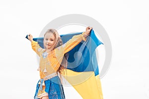 Girl carries fluttering blue and yellow flag of Ukraine in field.