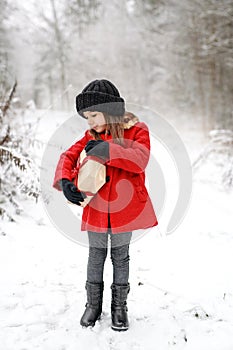 The girl is carrying a large gift box tied with a red festive ribbon