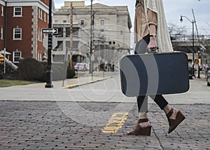 Girl carrying suitcase crossing road