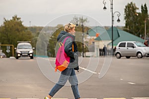 A girl in casual clothes crosses the road through a pedestrian crossing