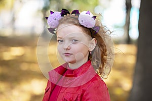 A girl in casual clothes and with a headband with Halloween horns