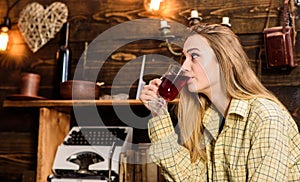 Girl in casual outfit sits in wooden vintage interior. Girl tomboy relax with glass with mulled wine in house of
