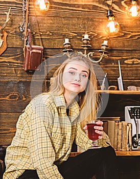 Girl in casual outfit sits in wooden vintage interior. Relax concept. Girl tomboy relax with glass with mulled wine in