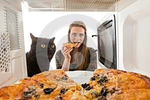 The girl and a cat looking in a microwave