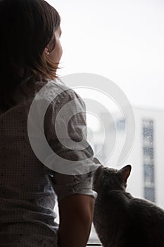 Girl and cat looking out the window
