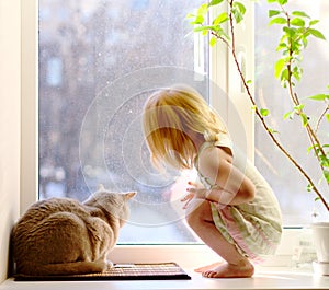 Girl and cat looking out of the window