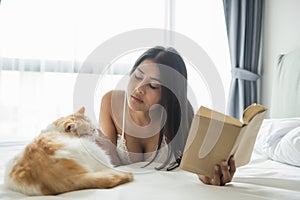 girl with cat read book on bed