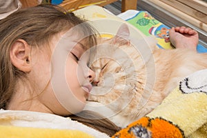 A girl and a cat are sleeping sweetly in bed