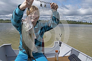 Girl Catching Big Bass In Boat On Lake