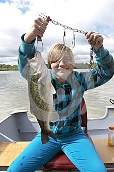 Girl Catching Big Bass In Boat On Lake