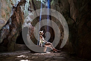 Girl in the cave under sun rays
