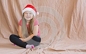 Girl celebrates new year and christmas wearing a santa claus siit hat and dreams of gifts copy space