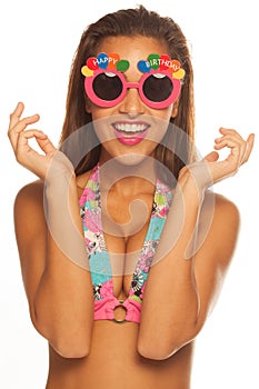 Girl celebrating wearing birthday sunglasses on white