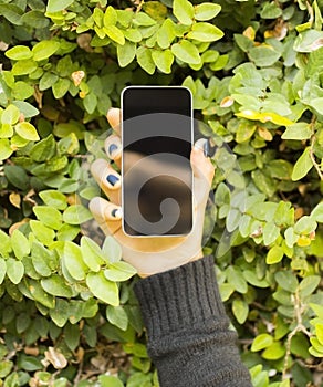 Girl with a cell phone against a background of foliage