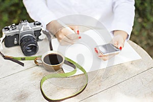 Girl with cell phone, diary, cup of coffee and old camera