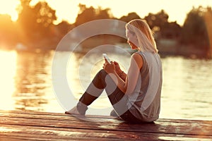 Girl with cellphone sitting on dock