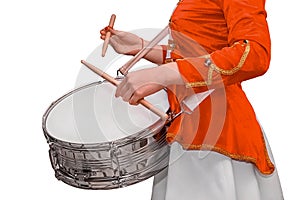 A girl in ceremonial red clothes plays with drumsticks on a drum on a white isolated background