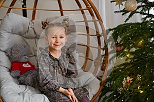 Girl in a chair near the Christmas tree