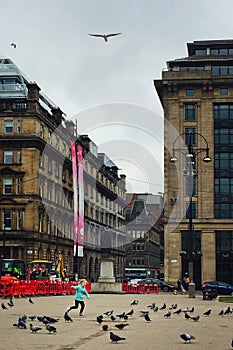 A girl chasing pigeons in the city square