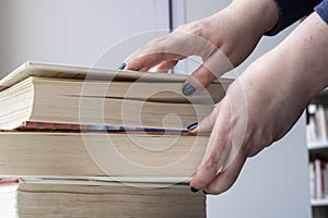 Girl is checking books at window. 4 thick or heavy books. Library