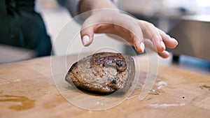 Girl chef checks finger pokes meat steak