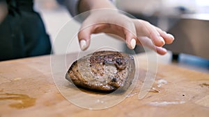 Girl chef checks finger pokes meat steak