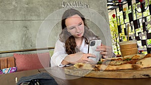 girl chef makes selfie photo with hot pizza from oven. Concept video blog in bright kitchen.