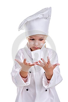 Girl chef white uniform isolated on white background. Looking opened-eyed at the floured palms. Floured face. Portrait