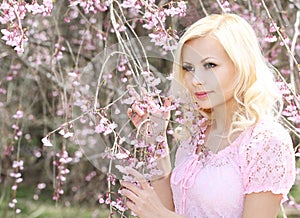 Girl with Cherry Blossom. Spring Flowers. Beautiful Blonde Woman