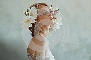 Girl in a chic long dress sitting on the floor. White wedding dress on the bride`s body. Beautiful light dress with a long hem, a