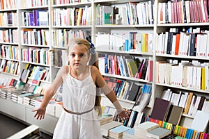 Girl child bemused a lot of books in a bookstore