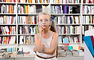 Girl child bemused a lot of books in bookstore