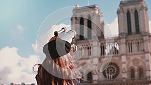 Girl child in beret looks through coin binocular. Slow motion. Notre-Dame de Paris. Female kid using view telescope.